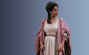 Nicole Heaston stands in period dress on stage an opera.